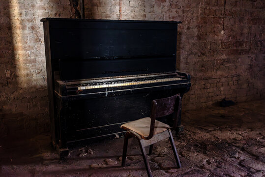 Old broken piano and chair in abandoned ruined mansion. Haunted house interior