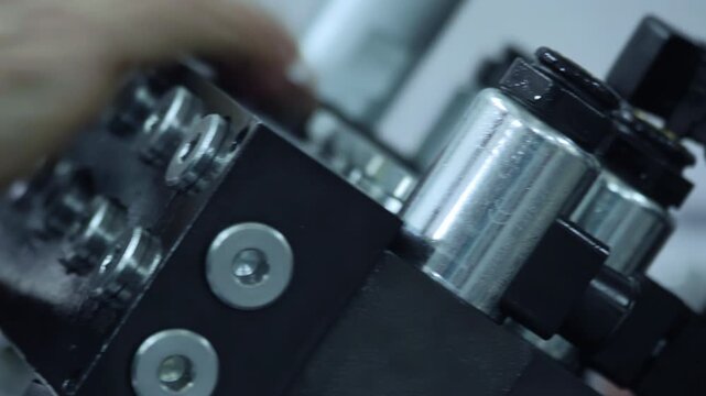 Hydraulic manifold closeup solenoid coils connectors. Handheld pan couplings.