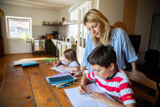Mother helping son with homework at kitchen table
