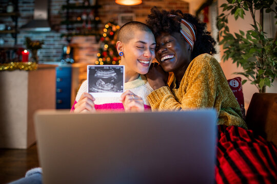Happy couple sharing ultrasound on video call at home