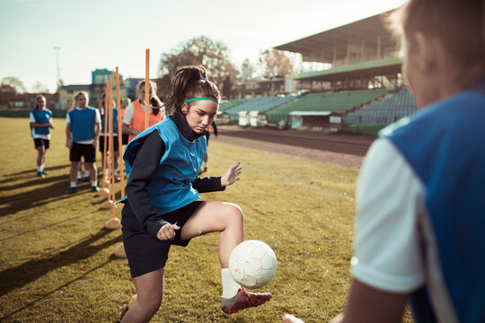 Teen girl juggling a soccer ball at team practice
