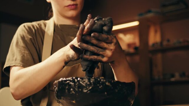 Woman potter works with clay on master class in studio. Working process in ceramic workshop. Potter making vase on pottery wheel. Handmade concept. 
