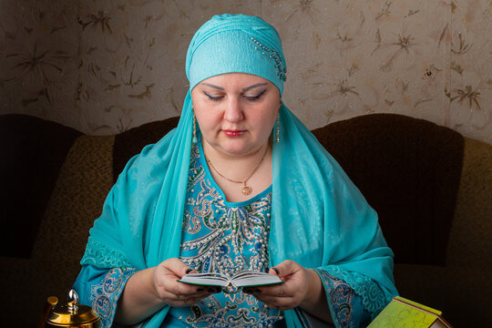 A Muslim woman in a blue hijab is reciting zikr before iftar