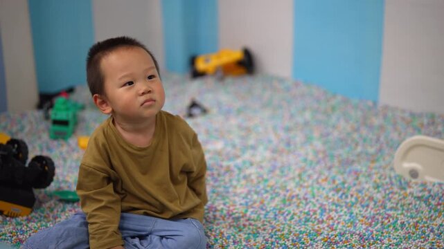 Boy sitting among colorful beads in an indoor play pit