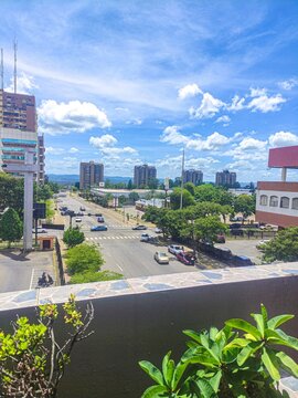 Vista aerea de avenida urbana con autos y edificios bajo cielo azul con nubes