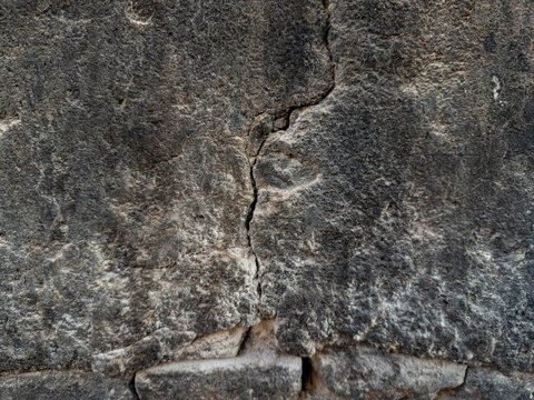 Broken crumbling plaster exposing old red bricks underneath, severely damaged concrete wall texture background