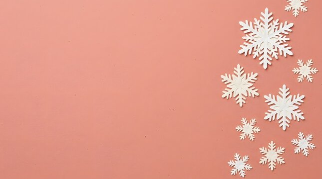 A beautiful and festive christmas background featuring delicate white snowflakes gracefully falling against a warm soft coral colored backdrop creating winter magic