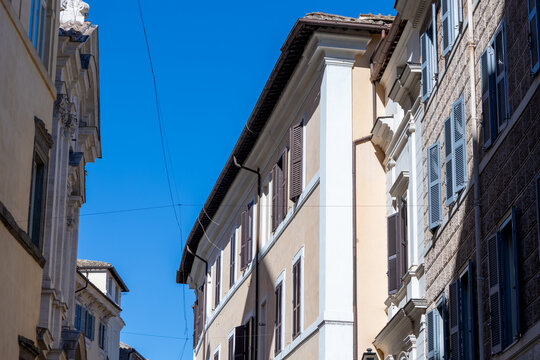 Historic buildings with shuttered windows against a clear blue sky on a street in central Rome, Italy