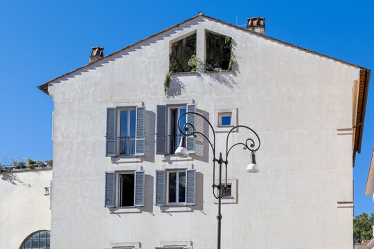 Traditional Roman building facade with grey shutters and ornate street lamp against blue sky in Rome, Italy