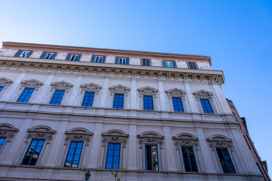 Low angle view of a Renaissance palazzo facade with blue windows against a clear sky in Rome, Italy