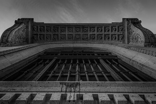Low angle view of an ornate stone archway with iron grille and coffered rosettes