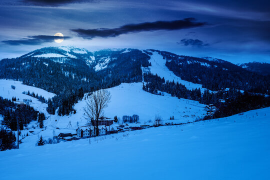 beautiful countryside of Ukraine at night. full moon over wonderful winter landscape in mountains. snow covered field and rolling hills. mysterious rural scenery