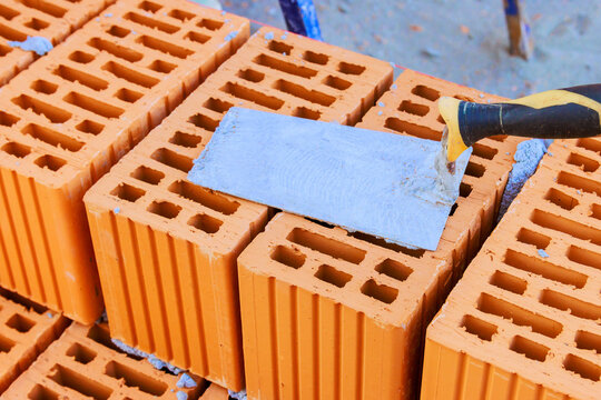Construction workers use trowel to apply mortar on bricks at site