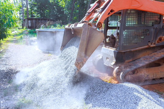 Tractor machine pours gravel on construction site equipment in works area