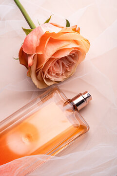 Rose and perfume bottle on soft peach fabric background