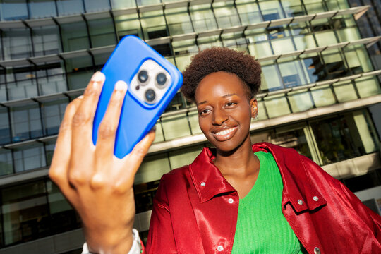 Gen Z woman taking selfie with smartphone in city street