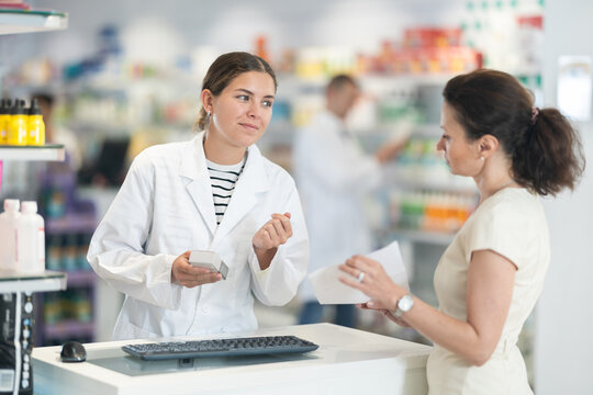 Friendly female pharmacist helping woman with prescription choosing medical supplies at drugstore
