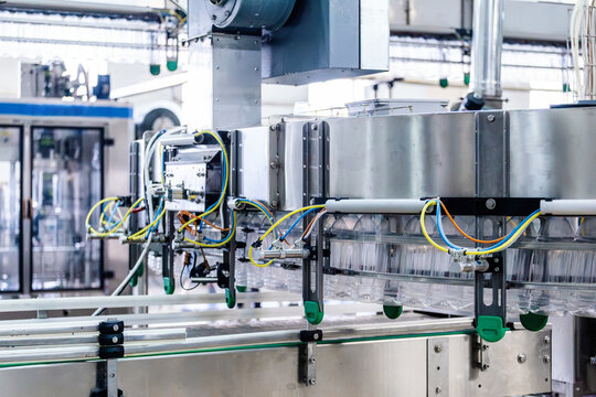 Industrial bottling line machinery with inverted empty PET bottles, automated conveyor transfer and container cleaning process for beverage factory packaging and mass production