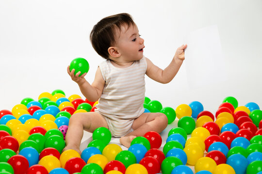 Baby playing with colorful balls and paper