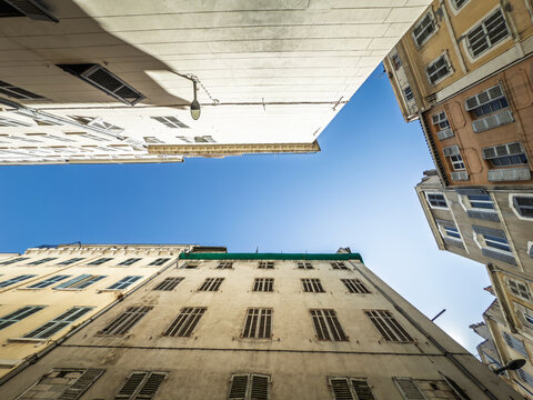 Low-angle view of residential buildings in the Noailles district, marseille, france, with apartment facades, shuttered windows and aging plaster walls illustrating housing in the city center.