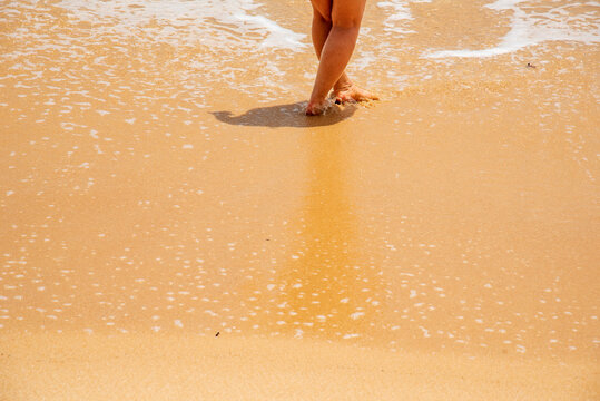 Cheerful asian woman barefoot walking on tropical summer beach. Woman walking along wave of sea water and sand on the beach. Enjoyment barefoot walk outdoor with freedom. Relaxation Travel Concept.