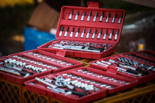 Open red plastic cases display sockets, ratchets, extension bars and driver bits on yellow crates. The arranged mechanical tool sets illustrate hardware shopping and equipment selection for repairs.