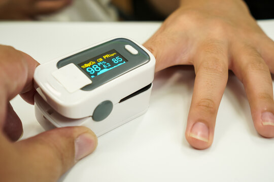 Two People Using Fingertip Pulse Oximeter for Assisted Blood Oxygen Monitoring at Home