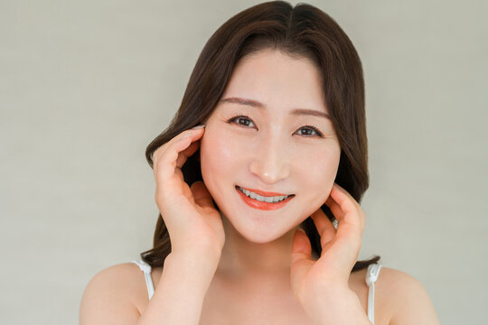 両手で頬に触れてうるおいを実感する40代女性。エイジングケアと保湿美容。
