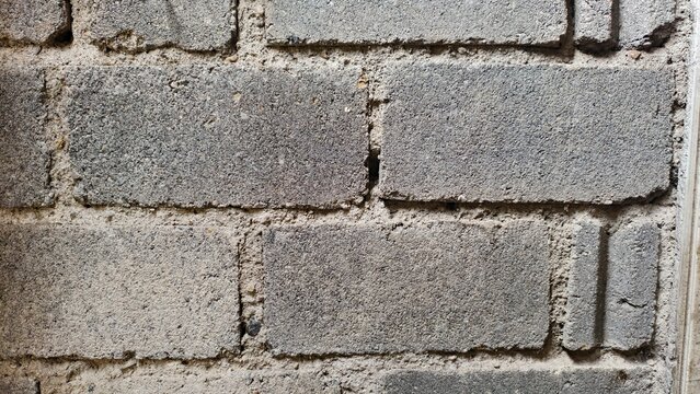 a close-up, front-facing view of a rustic wall built from textured grey concrete blocks (cinder blocks) bound together by rough, uneven mortar
