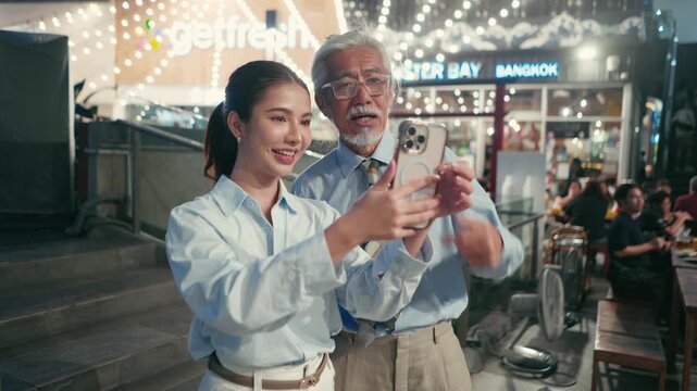 Coworkers laugh at their selfie with diners blurred behind them