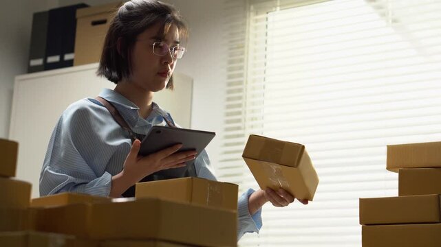 A seller uses a tablet beside stacked parcels in a packing area. Cardboard boxes and digital tools illustrate ecommerce order management, small business shipping, and preparation for parcel delivery.