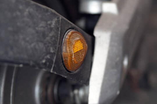 close-up shot of an orange reflector mounted on the metal frame of a vehicle or motorcycle.