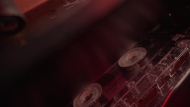 Hand loads a cassette tape into a dual deck player under red light. Gritty retro audio recording scene, ideal for police interrogation, wiretap evidence, crime mystery, and forensic thrillers.