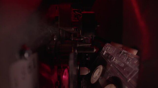 Hand loads a cassette tape into a dual deck player under red light. Gritty retro audio recording scene, ideal for police interrogation, wiretap evidence, crime mystery, and forensic thrillers.
