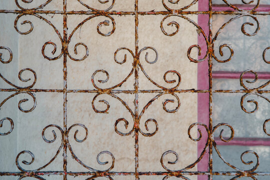 Antique Rusty Wrought Iron Window Grille Featuring Symmetrical Scrollwork Spirals and Patinated Metal Texture