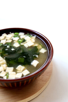 Traditional Japanese miso soup with tofu and seaweed in bowl.