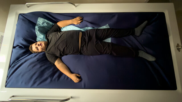 Man rests on hospital bed with blue mattress
