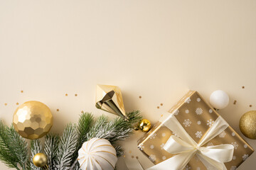 Christmas gift box with gold ornaments and pine branch arranged on cream background flat lay