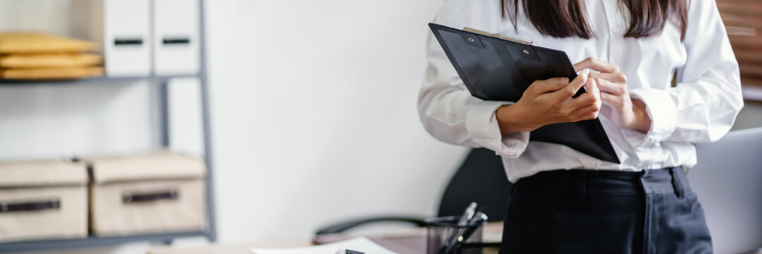 Business woman holding data clipboard with workplace background