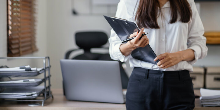 Business woman holding data clipboard with workplace background