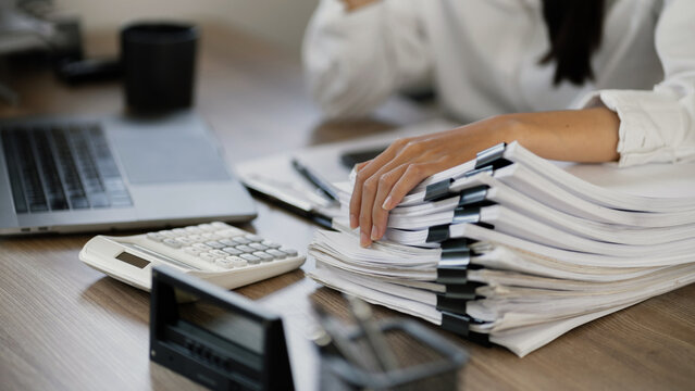 Business employee with stack of file spreadsheets at office desk
