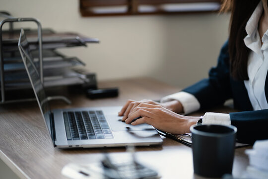 Businesswoman using laptop browsing data on internet in office desk