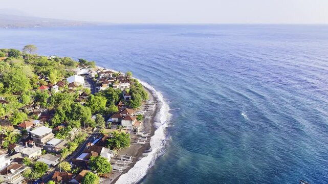 Jemeluk Bay in Amed, eastern Bali, Indonesia, features clear turquoise waters and a curved coastal shoreline - drone shot