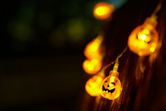 Glowing Halloween pumpkin light string on a wooden fence at night