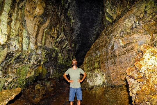 A man explores a dark lava tube cave in the Galapagos