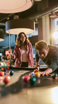 Young friends playing billiards in a stylish indoor lounge, sharing a relaxed moment of leisure, skill and friendly competition