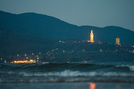 illuminated Lady Buddha statue and Linh Ung Pagoda above coastline with sea waves and mountains in Da Nang, Coastal landscape with ocean waves and Son Tra Peninsula at night, Danang Vietnam