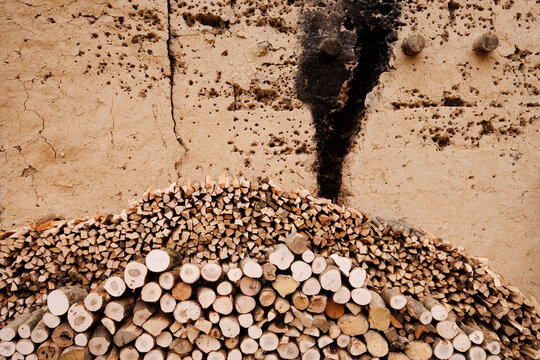 Stack of cut firewood arranged against cracked wall