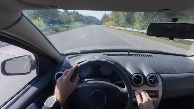 Driving car POV interior view of hands on steering wheel along highway