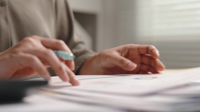 Accounting and finance, female accountant marking financial documents with pen, checking figures and using calculator at office desk for tax preparation, audit, bookkeeping and budget verification.